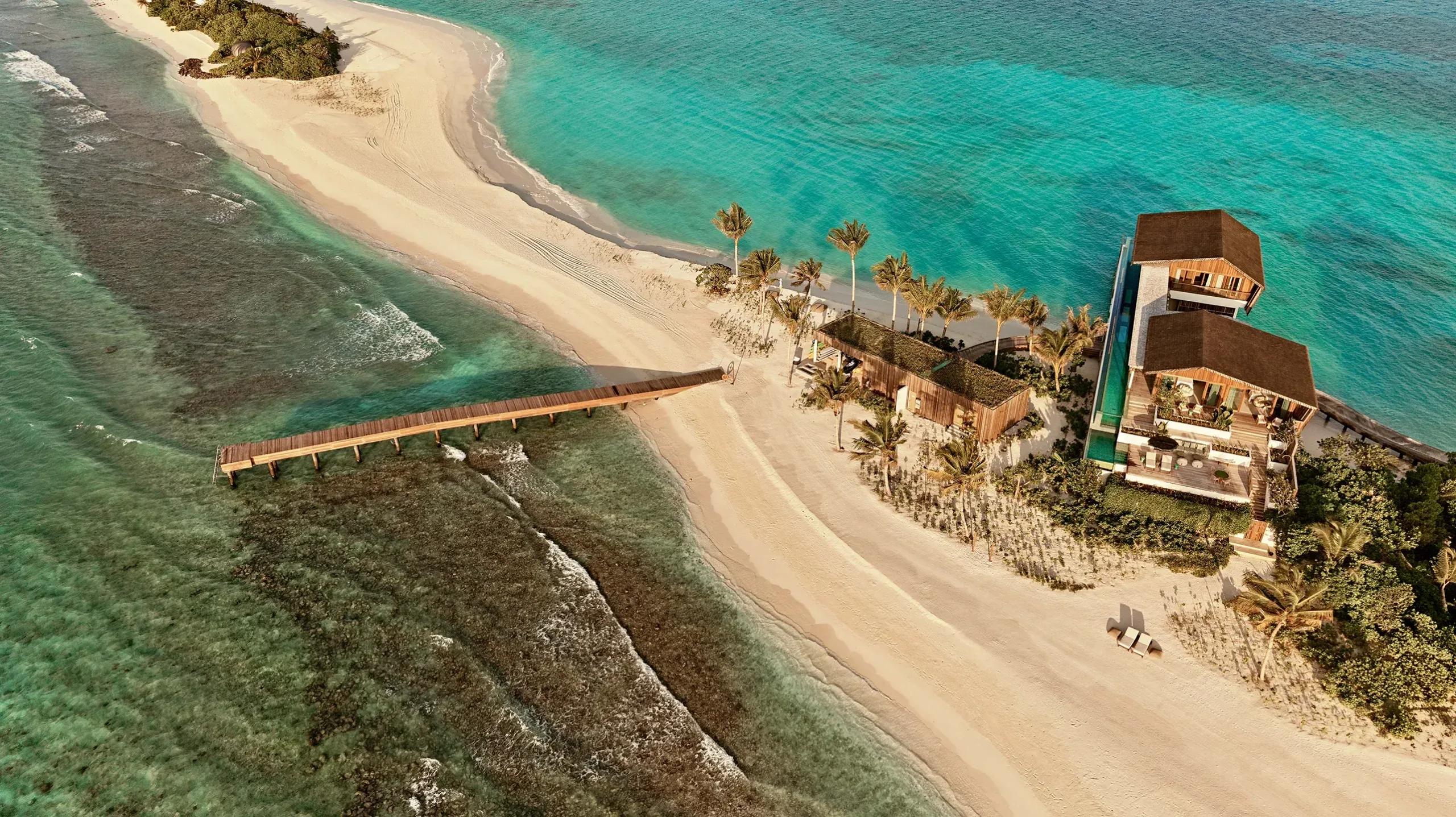 Aerial view of a residence on .Here's Somewhere island in Baa Atoll, its private pool and jetty set along a shared sandbank ringed by reef