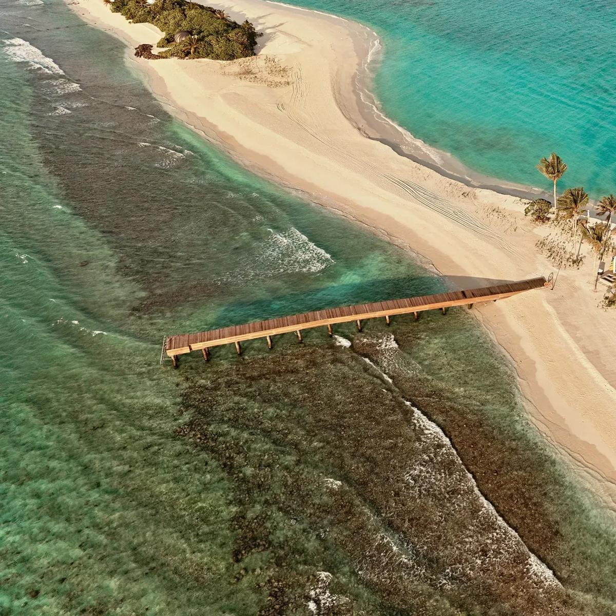 Aerial view of a residence on .Here's Somewhere island in Baa Atoll, its private pool and jetty set along a shared sandbank ringed by reef