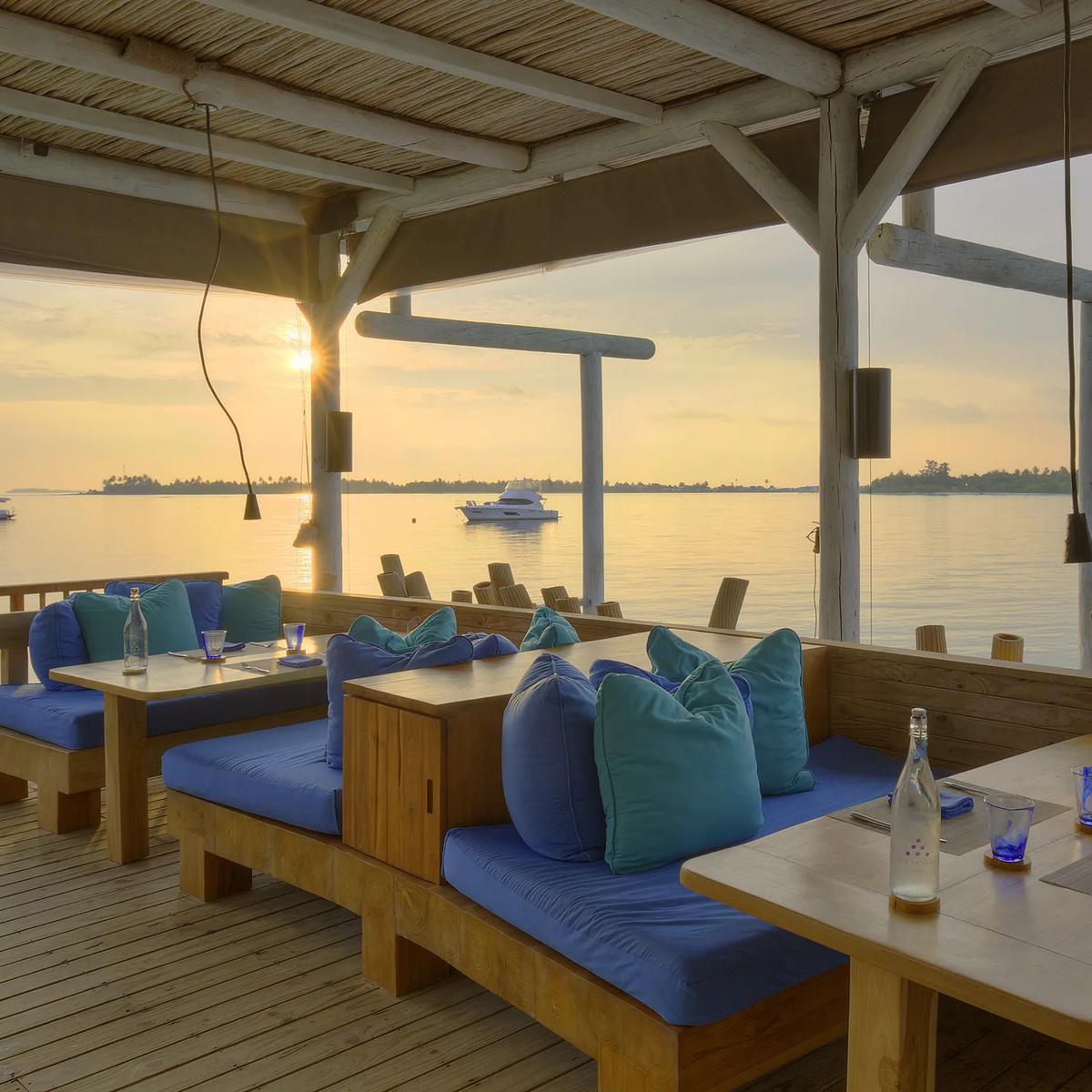 Chill Bar's thatched roof and timber beams silhouetted against a sunset sky over the reef