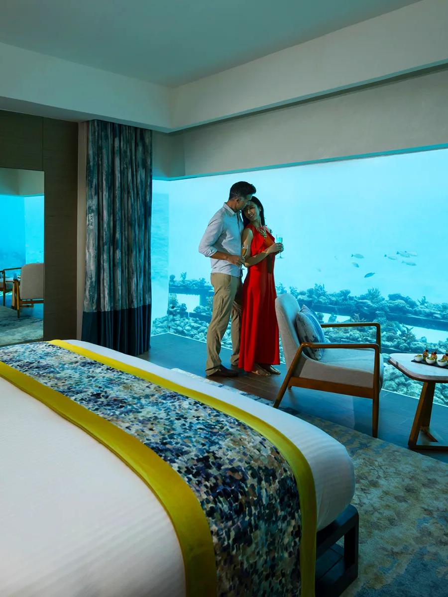 A couple relaxing on the deck of an Aqua Villa above the lagoon