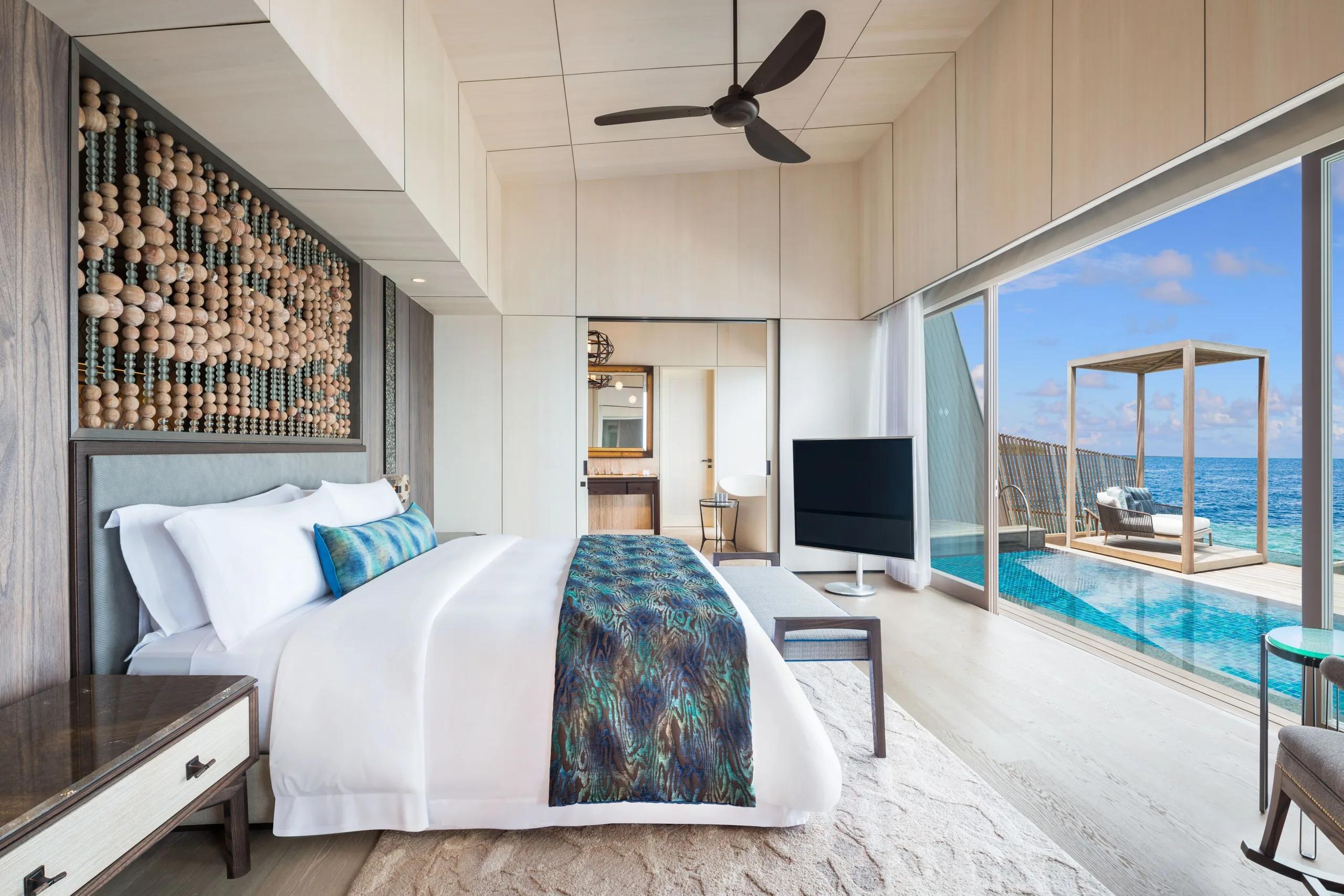 The bedroom of an Overwater St. Regis Suite, set beyond its dedicated living and dining area