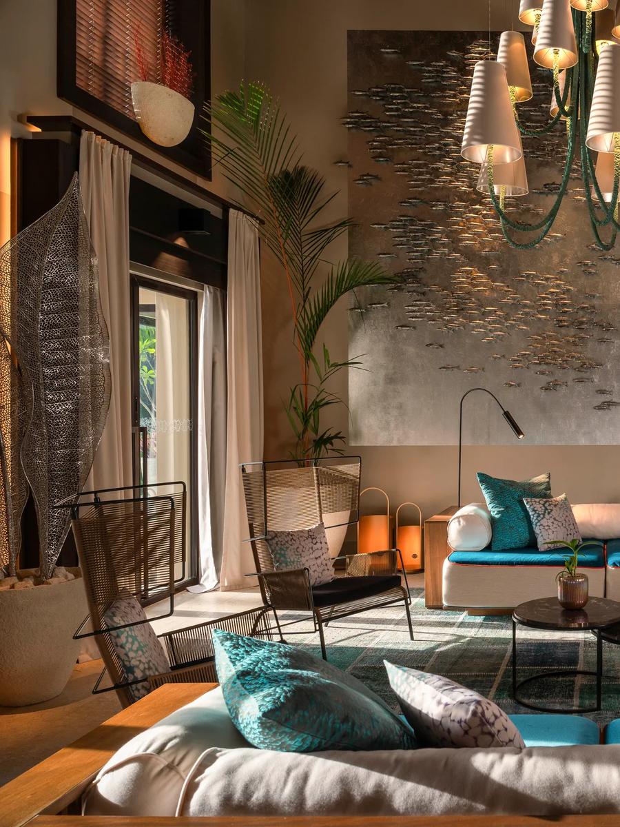 A double-height lounge inside Nirolhu Private Residence, with large-scale artwork of a sea turtle and a school of fish on the far wall