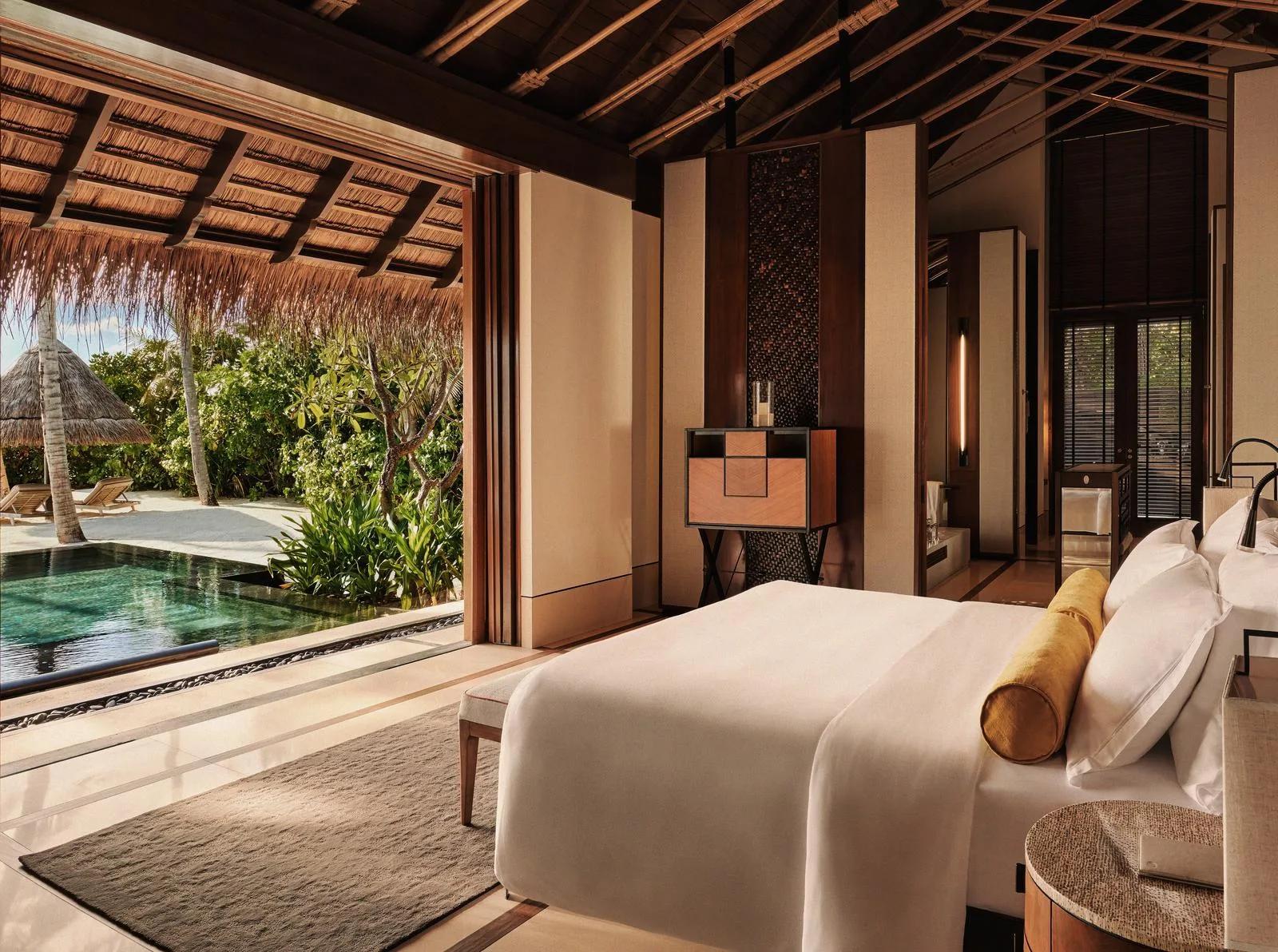 The bedroom of a Beach Villa with Pool at One&Only Reethi Rah, opening onto its private pool with the beach beyond