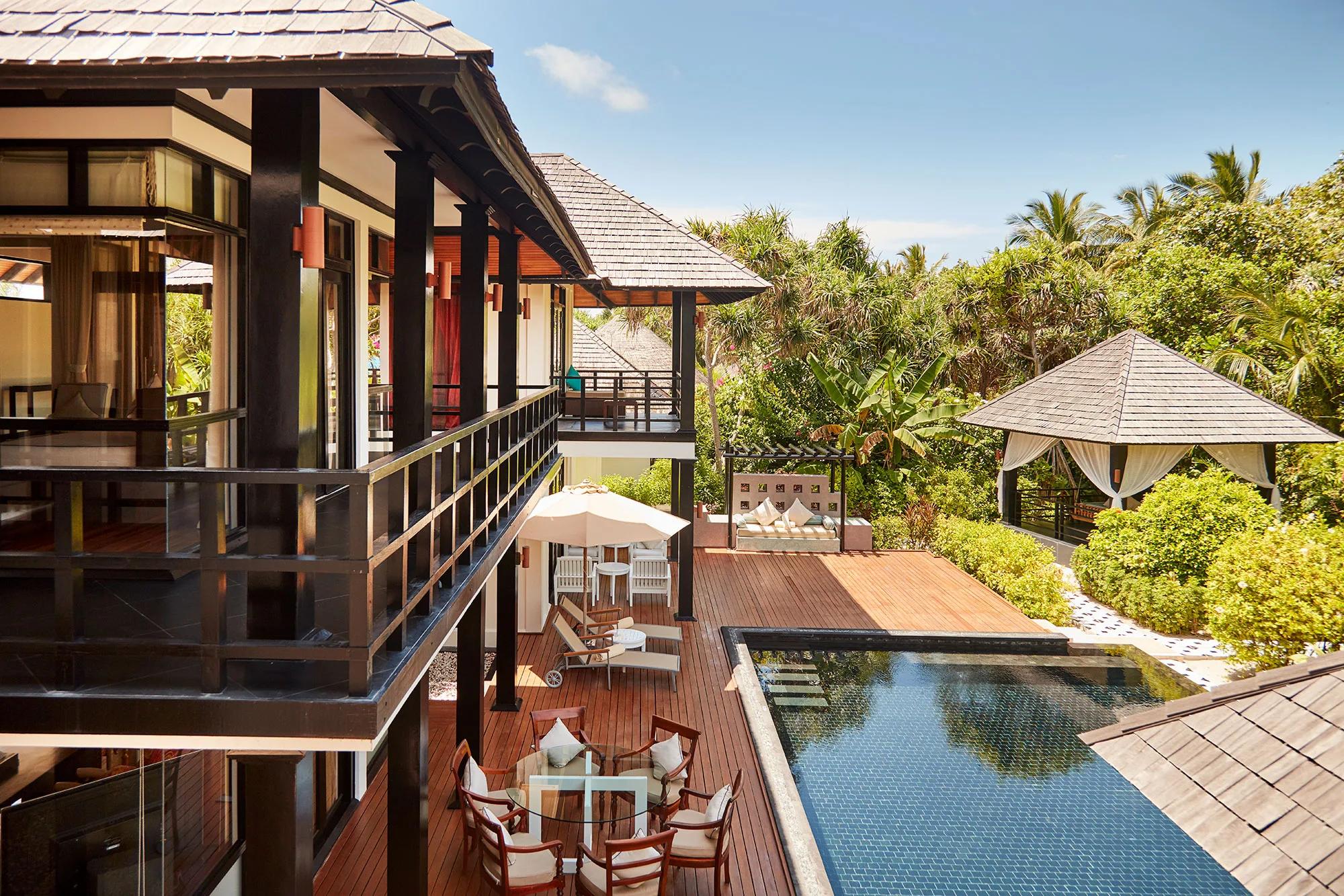 A two-storey Celebrity Retreat villa with its private pool, outdoor dining table and lounge seating in a garden setting