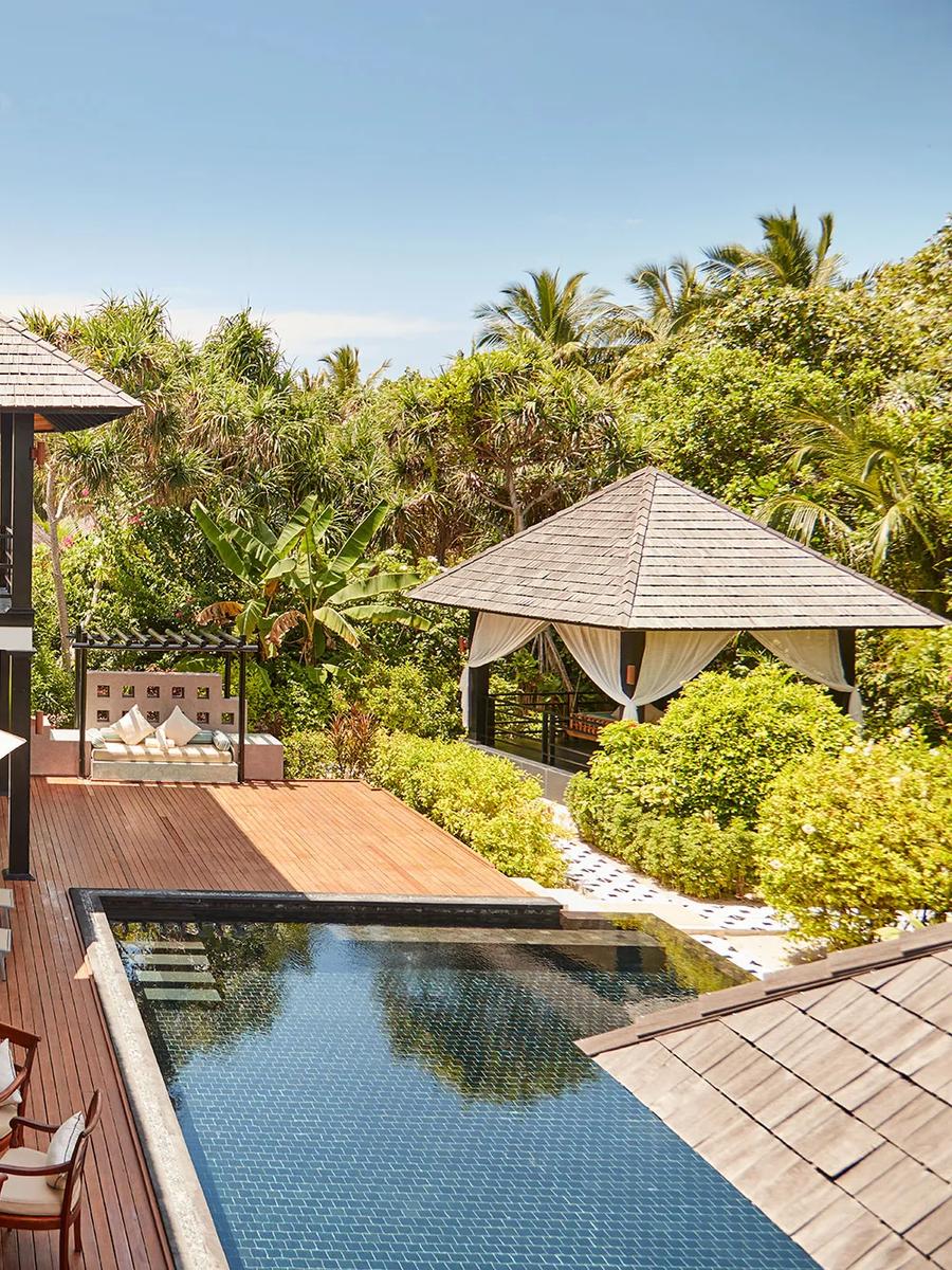 A two-storey Celebrity Retreat villa with its private pool, outdoor dining table and lounge seating in a garden setting