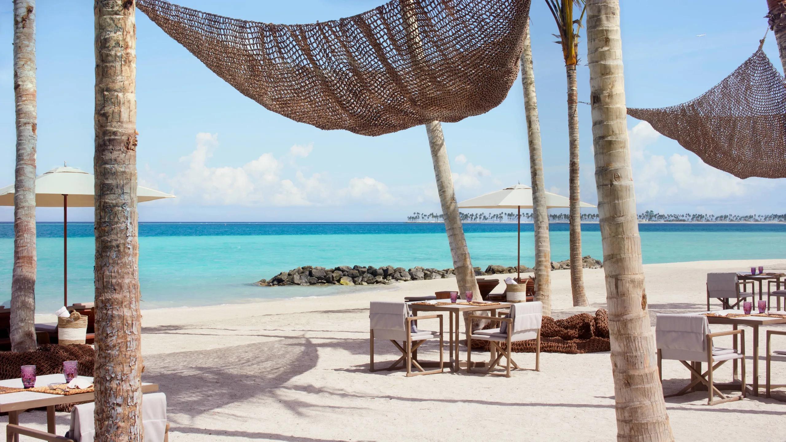 Beach Shack's dining tables strung with woven hammocks over the sand