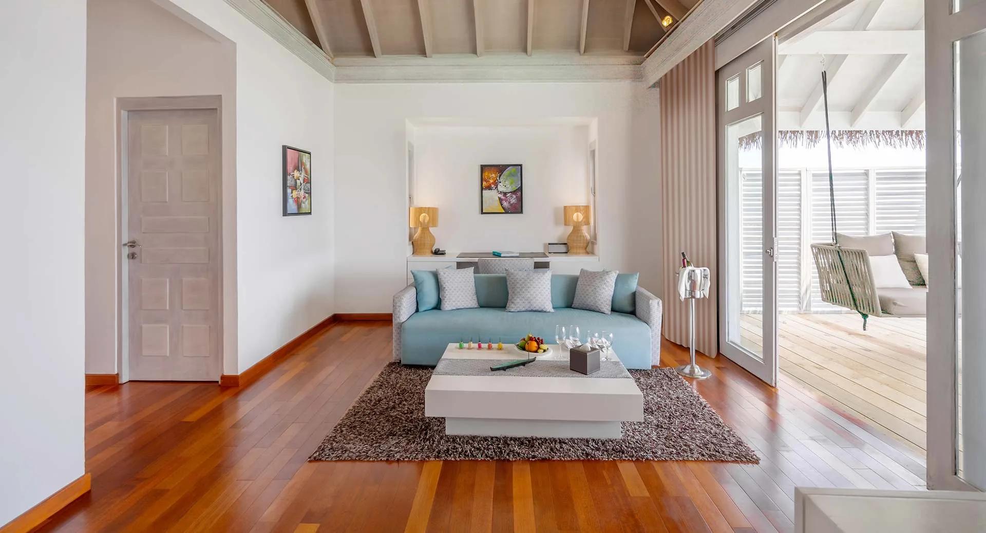 The living area of an Over Water Suite with Private Pool, with a hammock swing on the deck beyond