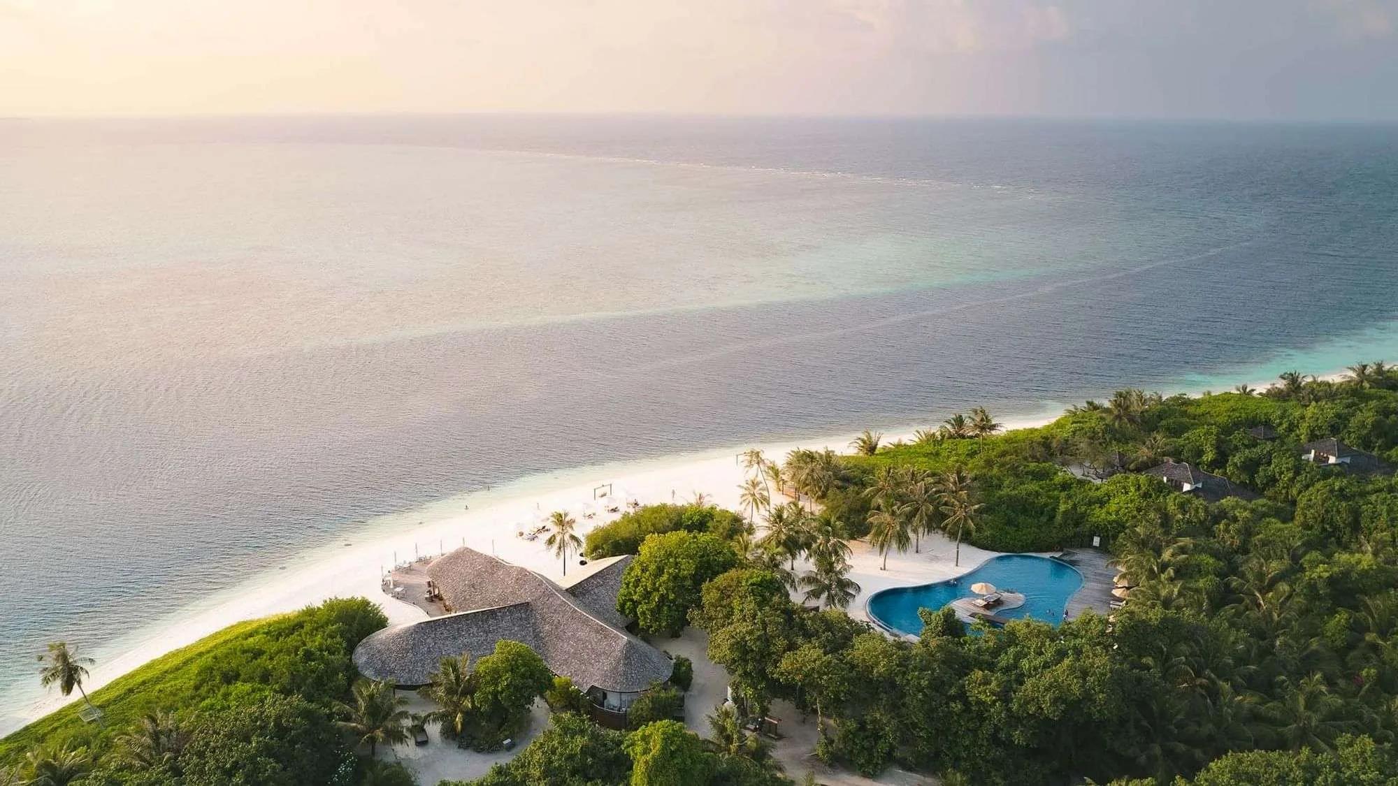 Aerial view of the shared infinity pool beside Meeru Bar & Grill at sunset, Hideaway Beach Resort & Spa