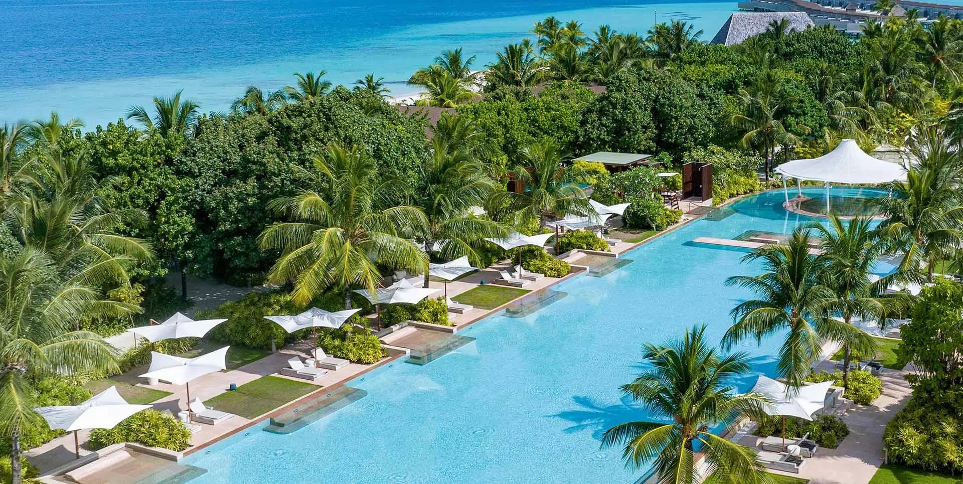 An aerial view of Kuda Villingili Resort Maldives' 150-metre pool, the largest swimming pool in the Maldives, framed by the island and lagoon