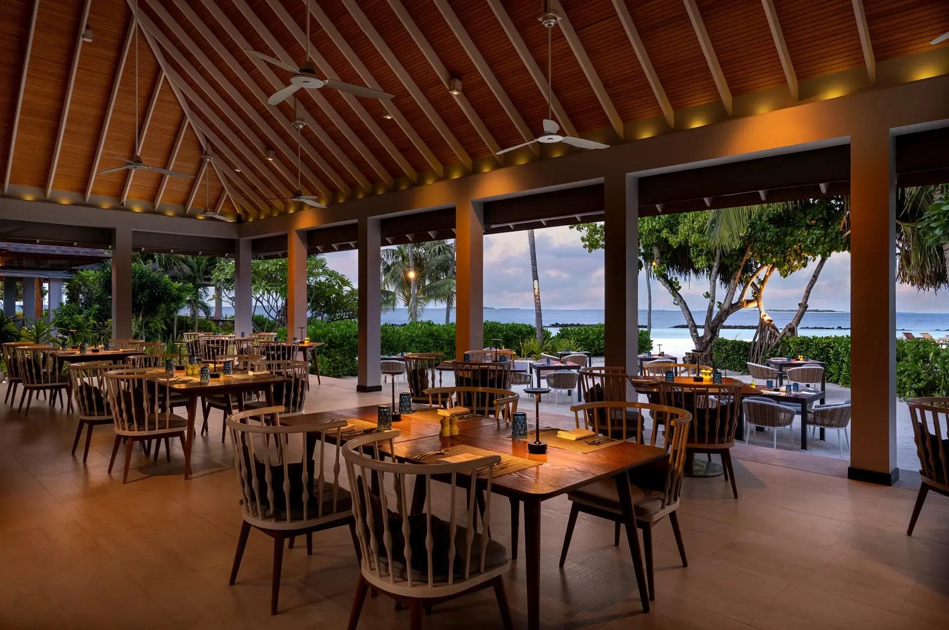 The open-air dining pavilion at Jade at dusk, tables set beneath a peaked wooden roof