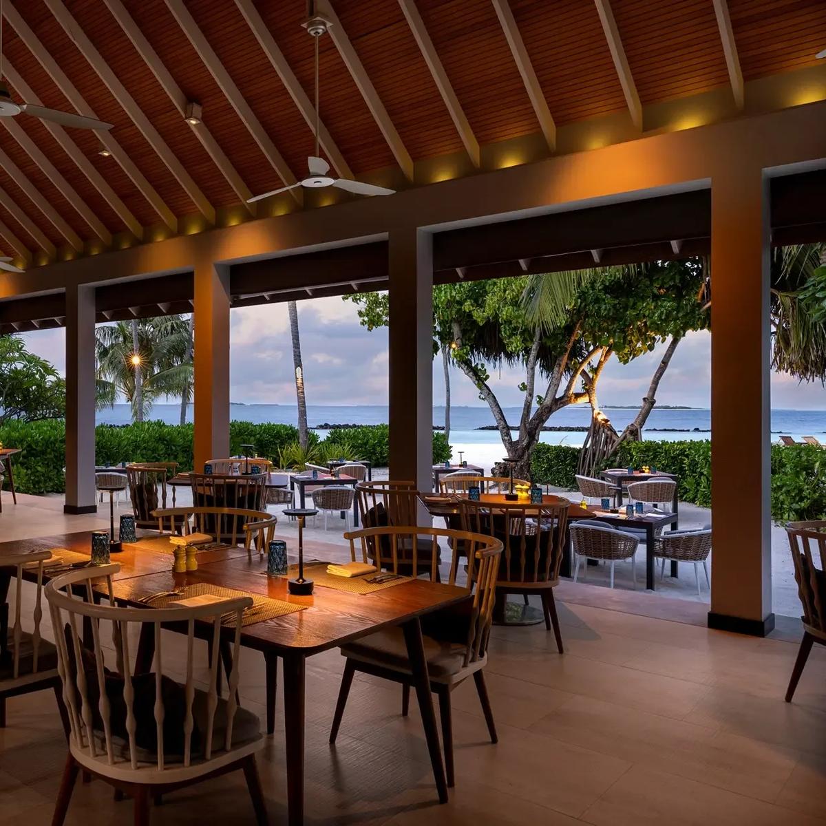 The open-air dining pavilion at Jade at dusk, tables set beneath a peaked wooden roof