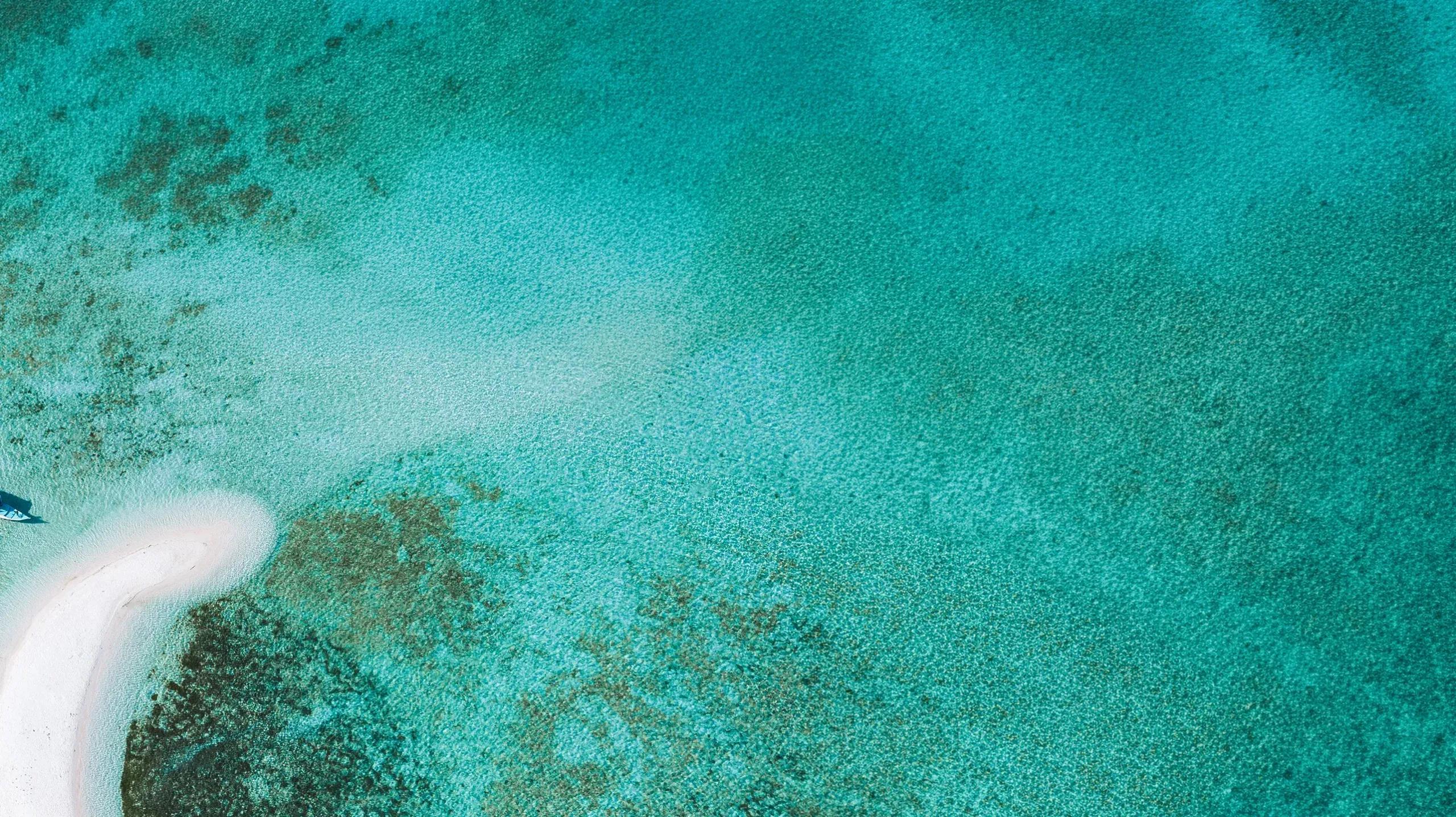 Aerial view of open water and reef structures beyond .Here's private islands