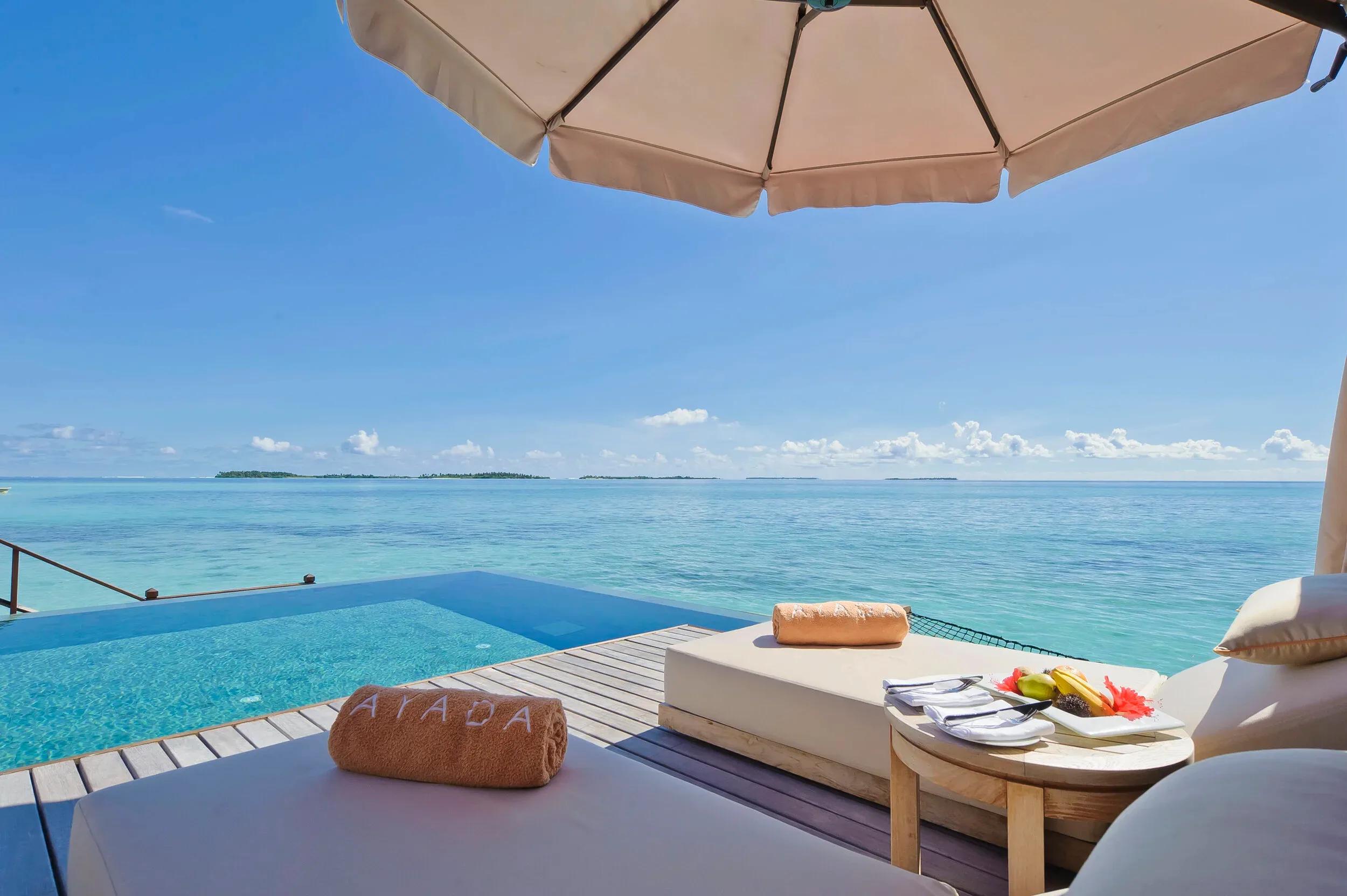 An Ocean Villa's lounging deck, sun loungers and a rolled Ayada towel beside the open lagoon