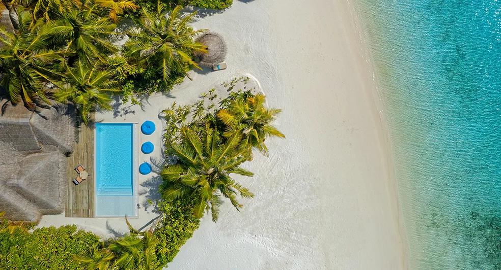 Aerial view of a two-bedroom family pool villa and its surrounding lagoon at Anantara Dhigu