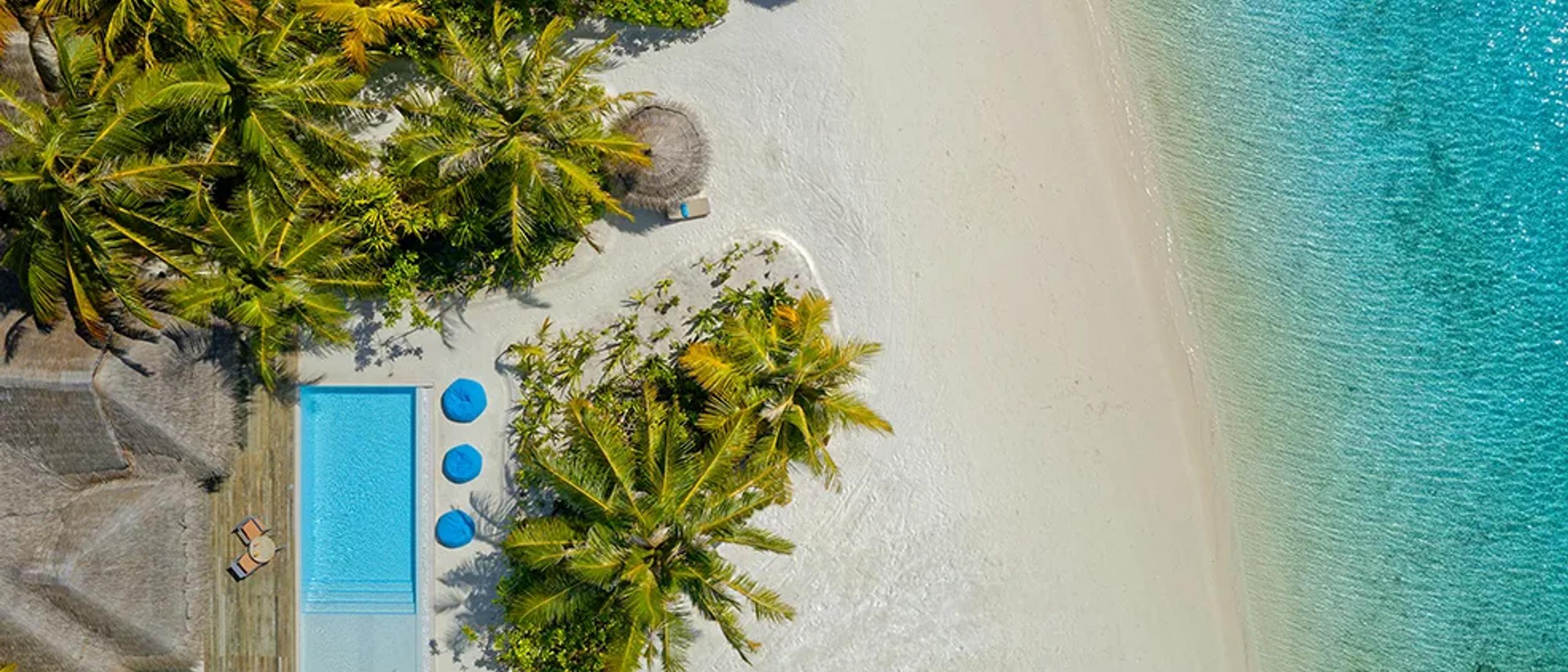 Aerial view of a two-bedroom family pool villa and its surrounding lagoon at Anantara Dhigu