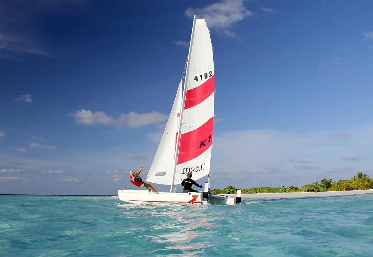 A Topcat catamaran sailing past the island with an instructor and guest aboard