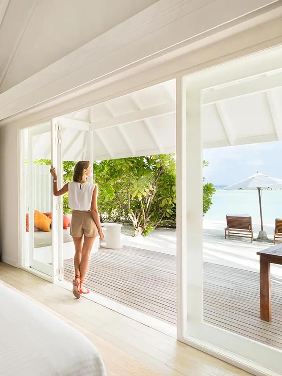 Interior of a Beach Villa, with a guest walking out through open doors toward the beachfront terrace