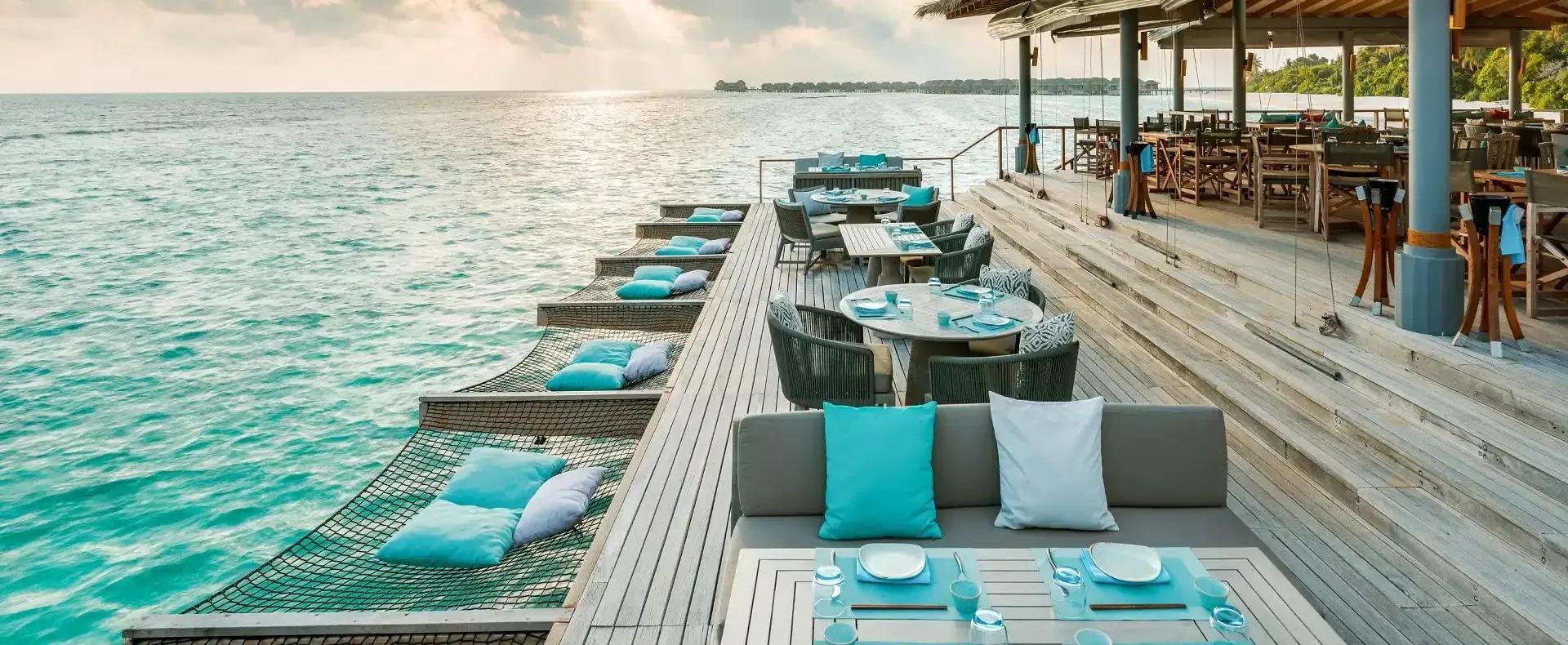 Lagoon Bar's overwater hammock day beds strung along the jetty rail above turquoise water