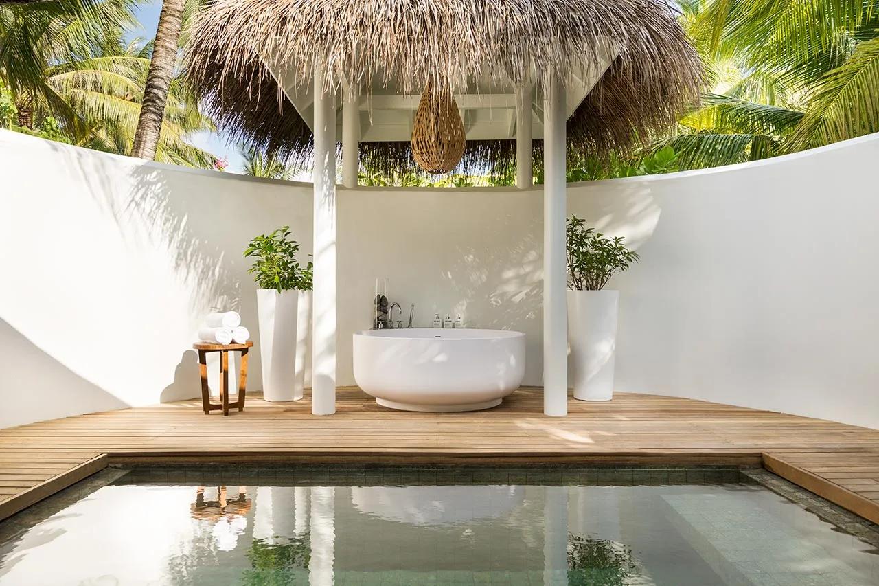 An open-air ensuite courtyard at a Beach Pool Villa, with a freestanding tub and plunge pool beneath a thatched sunshade