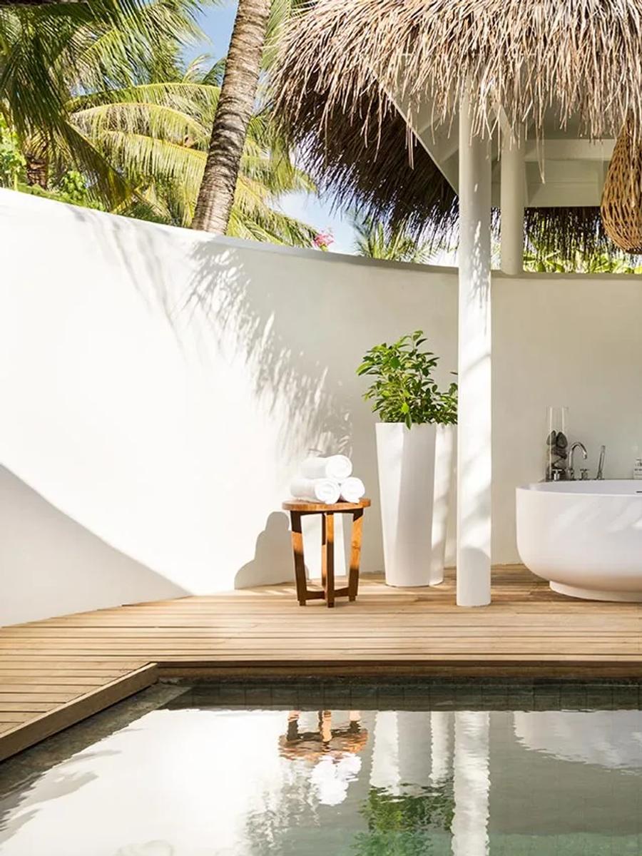 An open-air ensuite courtyard at a Beach Pool Villa, with a freestanding tub and plunge pool beneath a thatched sunshade
