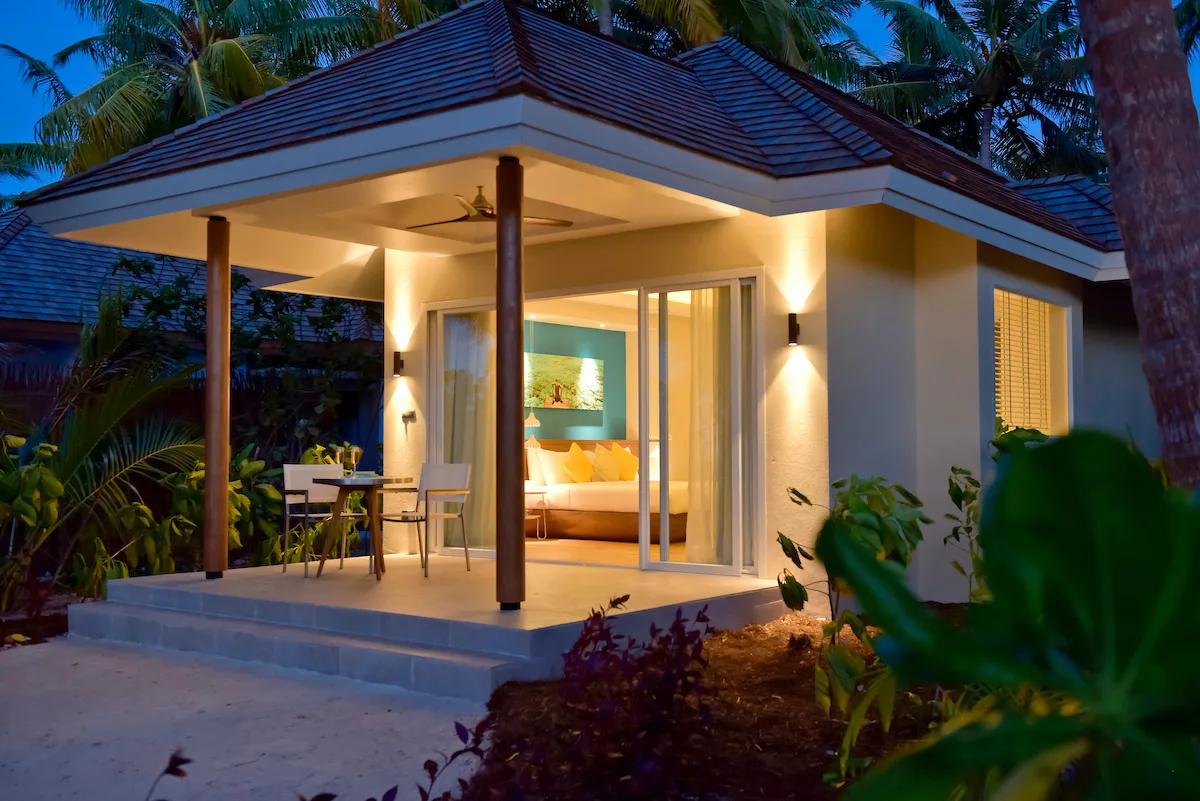A Sunset Beach Pool Villa lit for the evening, its terrace open toward the beach