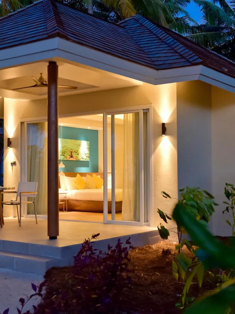 A Sunset Beach Pool Villa lit for the evening, its terrace open toward the beach