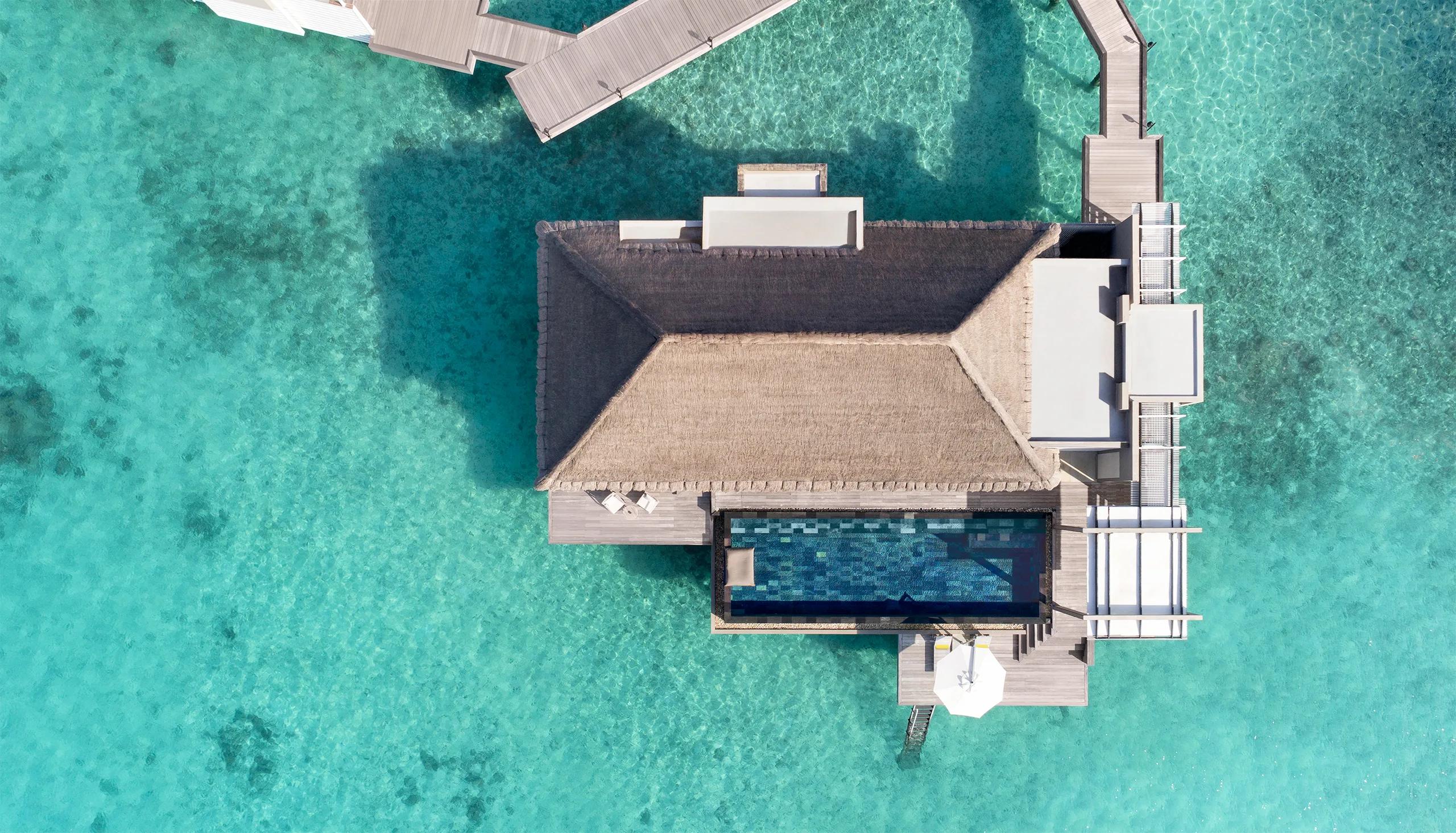 Aerial view directly above a Cheval Blanc Randheli overwater villa, its private infinity pool extending toward open water