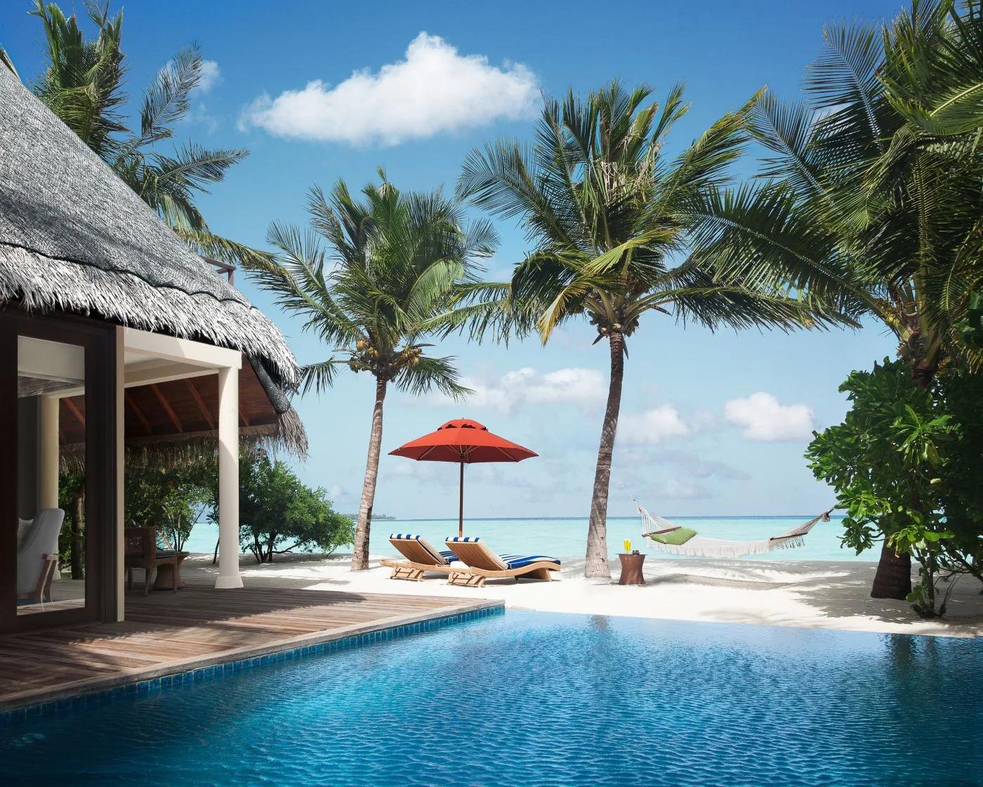 A One Bedroom Sunset Beachfront Suite's private pool by day, a hammock strung between two palms beside the loungers