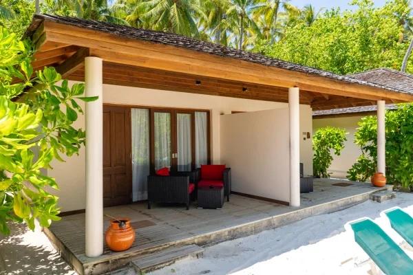 The covered veranda of an Adjacent Beachfront Villa, with rattan seating steps from the beach loungers