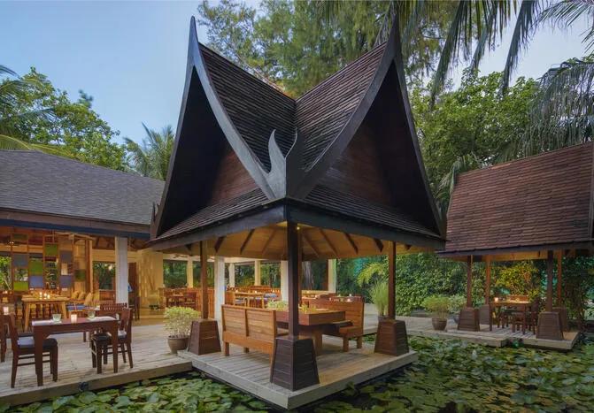 Suan Bua's steep pavilion roofline set over the resort's lily pond, tables laid for dinner