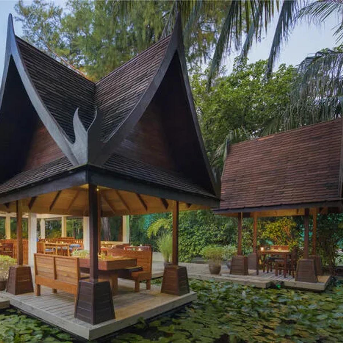 Suan Bua's steep pavilion roofline set over the resort's lily pond, tables laid for dinner