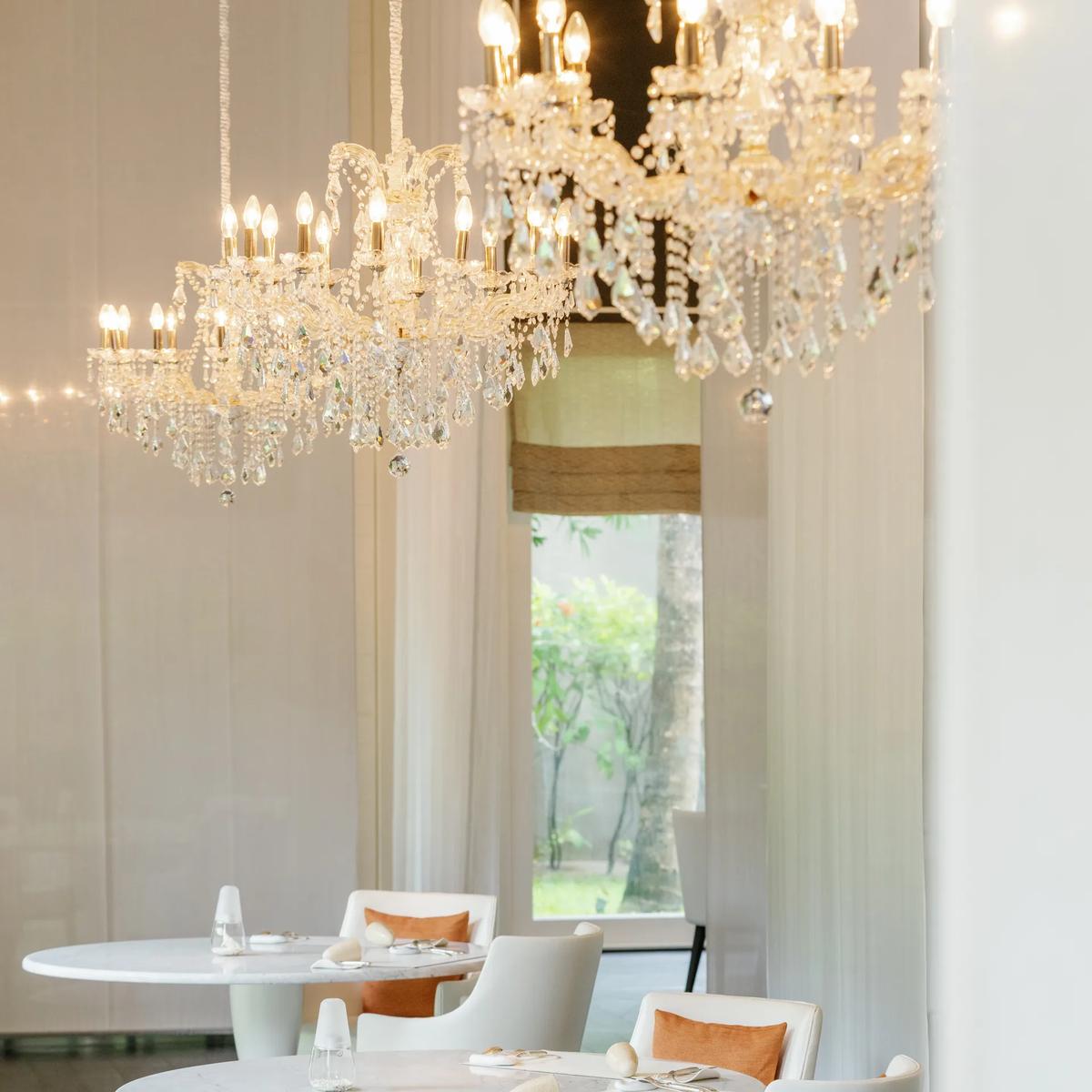 Le 1947's dining room, three crystal chandeliers hanging above a long table set for dinner