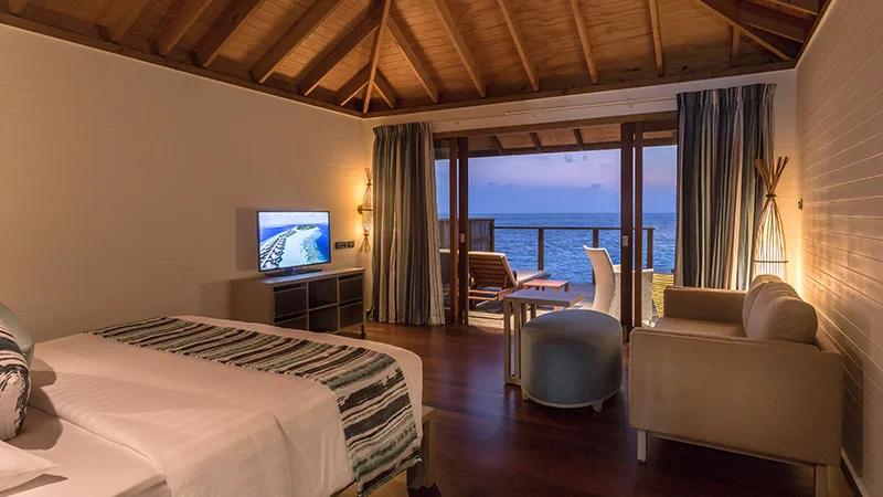 Romantic Ocean Villa interior at dusk, with the private deck opening straight onto the lagoon