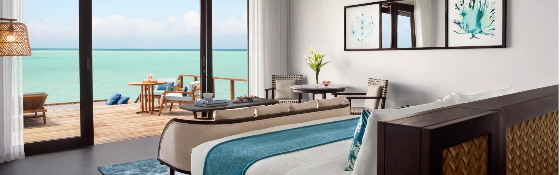 Deluxe Over Water Pool Villa deck with an infinity pool running to the open lagoon at dusk