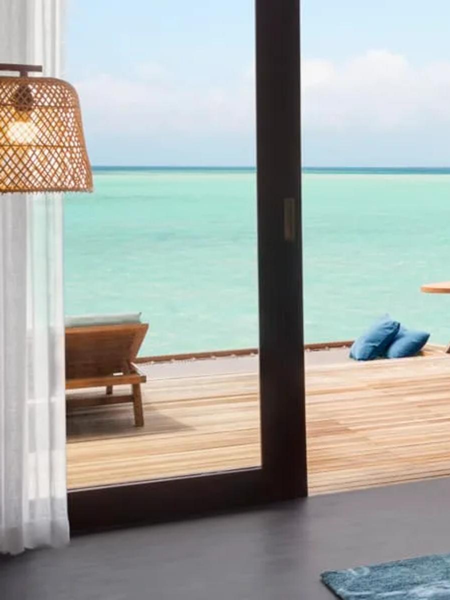 Deluxe Over Water Pool Villa deck with an infinity pool running to the open lagoon at dusk