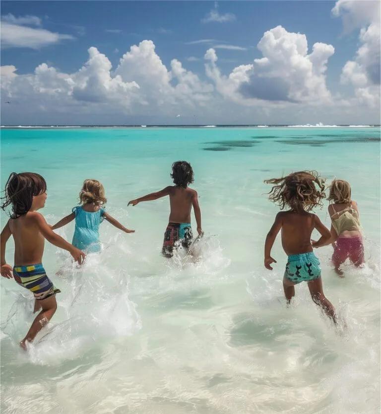 Five children running through shallow, clear water at the beach, splashing as they go