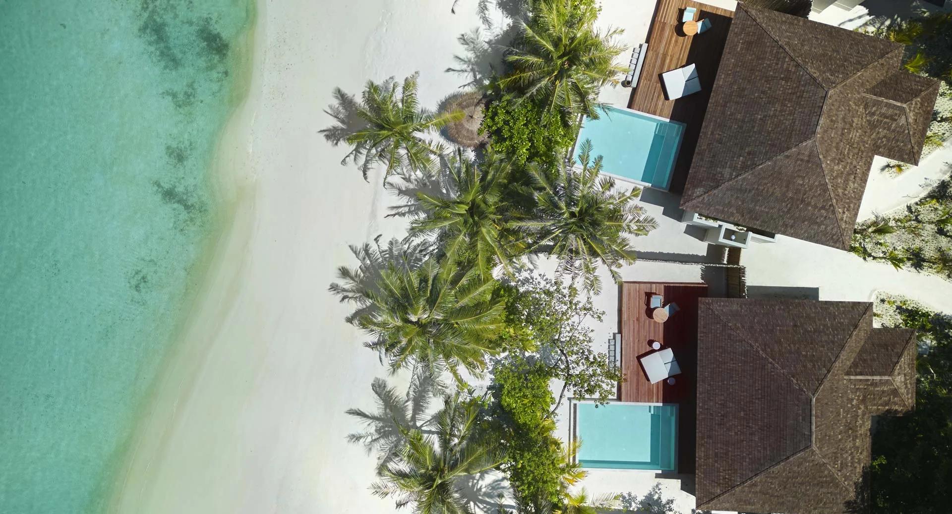 Aerial view of Beach Pool Villas set among palm trees on the edge of the lagoon