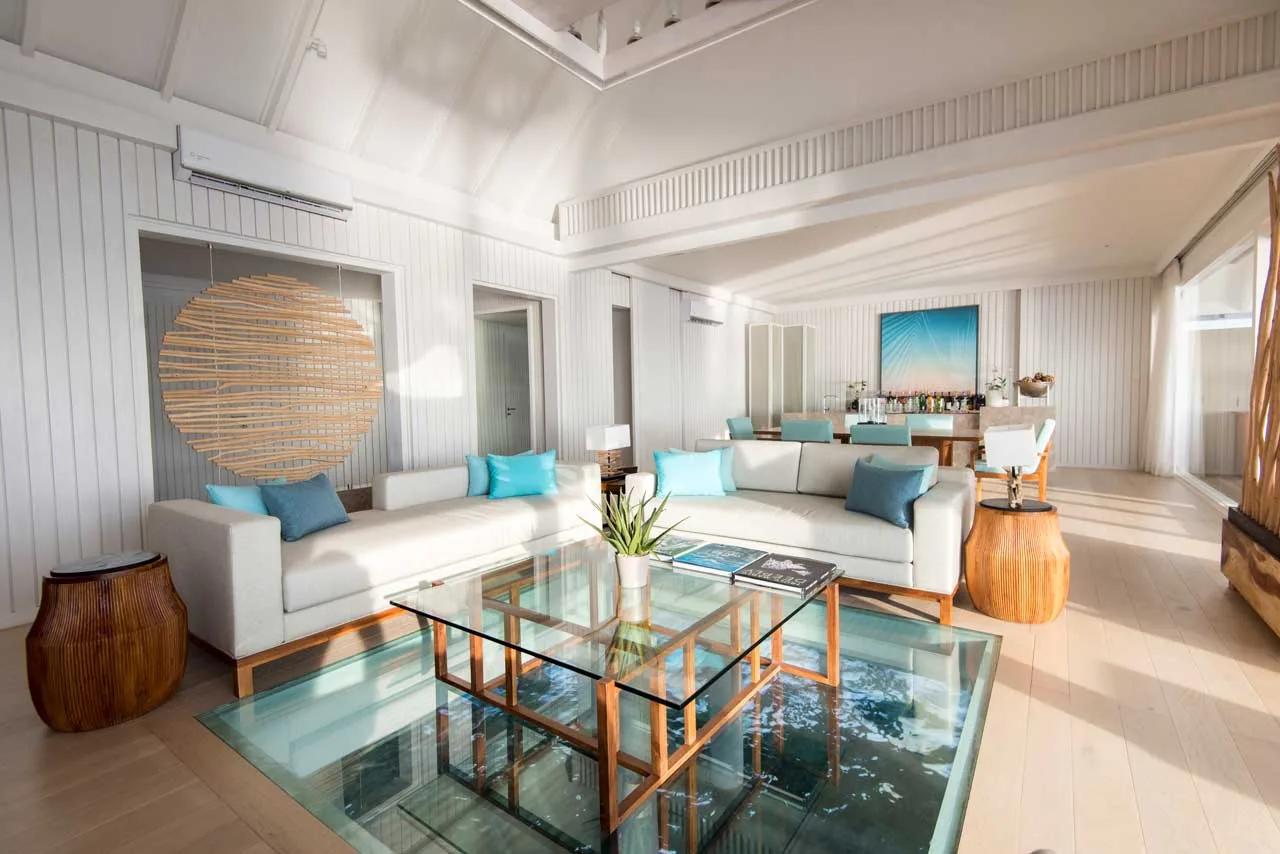 The LUX* Villa's living and dining room, with a glass floor panel set into the flooring over the water