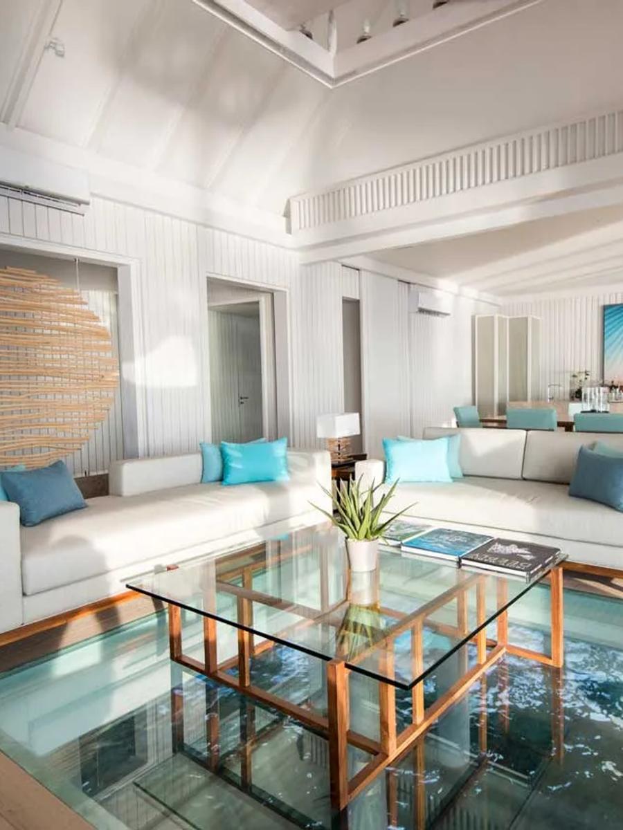 The LUX* Villa's living and dining room, with a glass floor panel set into the flooring over the water