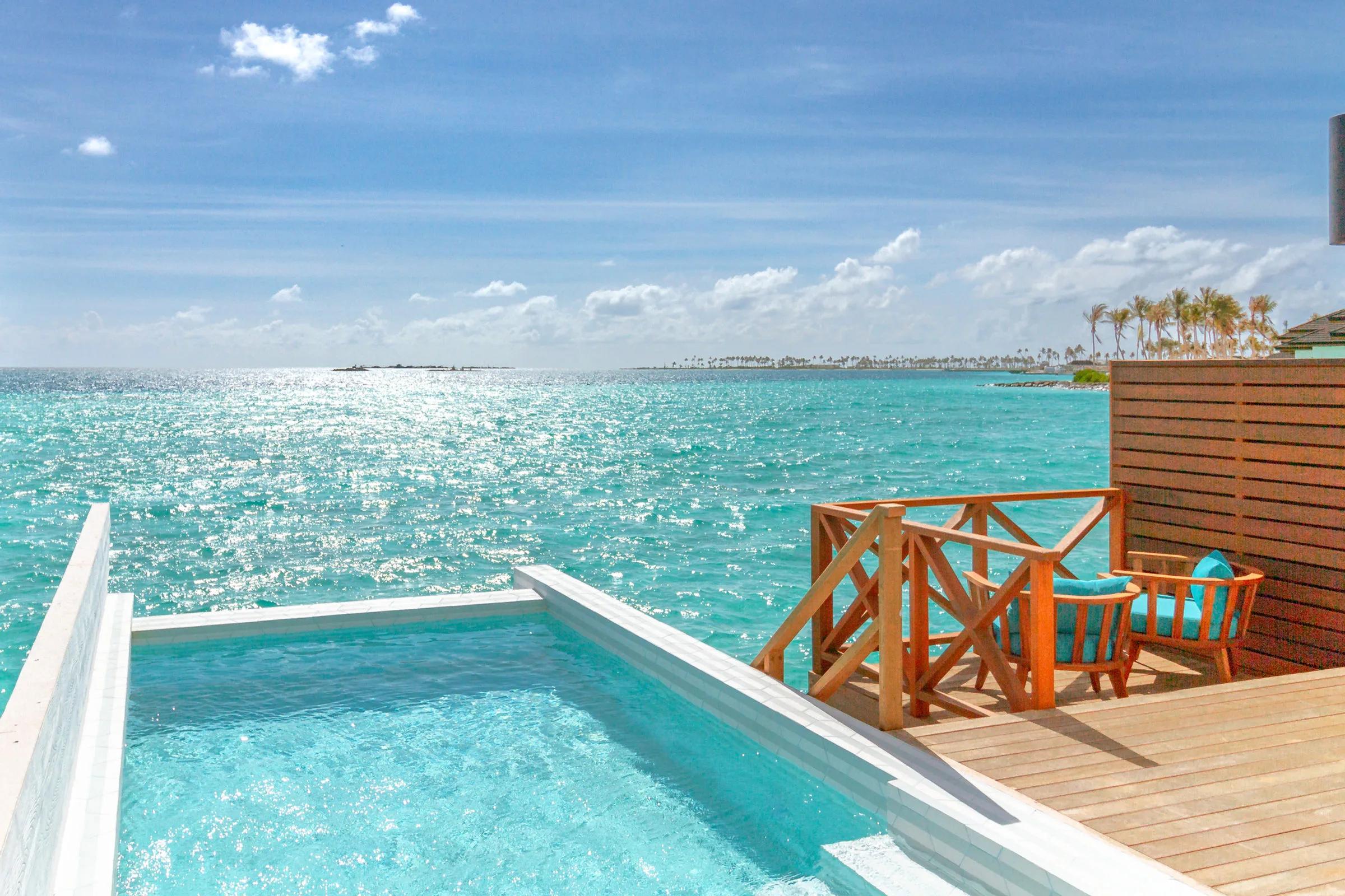 A Lagoon Suite Pool's wade-in pool and sundeck, open ocean and a neighbouring island beyond