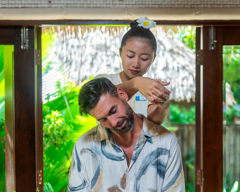 A guest receiving a neck and shoulder massage in an open-air treatment room at Orchid Spa