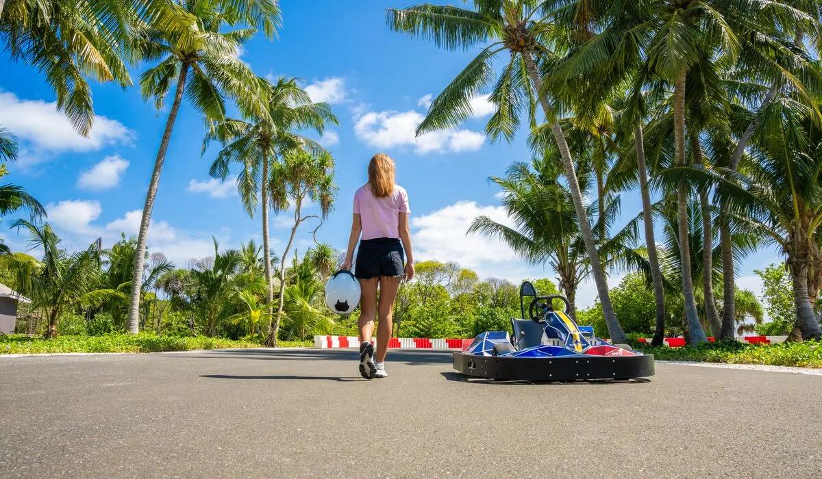 A guest walking toward a go-kart on a track threaded through the island's palm trees