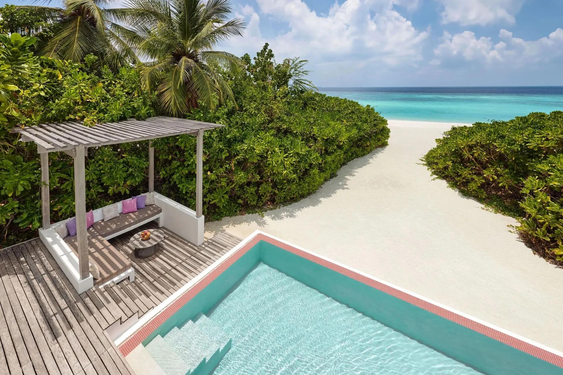 A private pool and shaded pergola lounge on a One Bedroom Beach Villa's deck, a sandy path leading down to the beach beyond