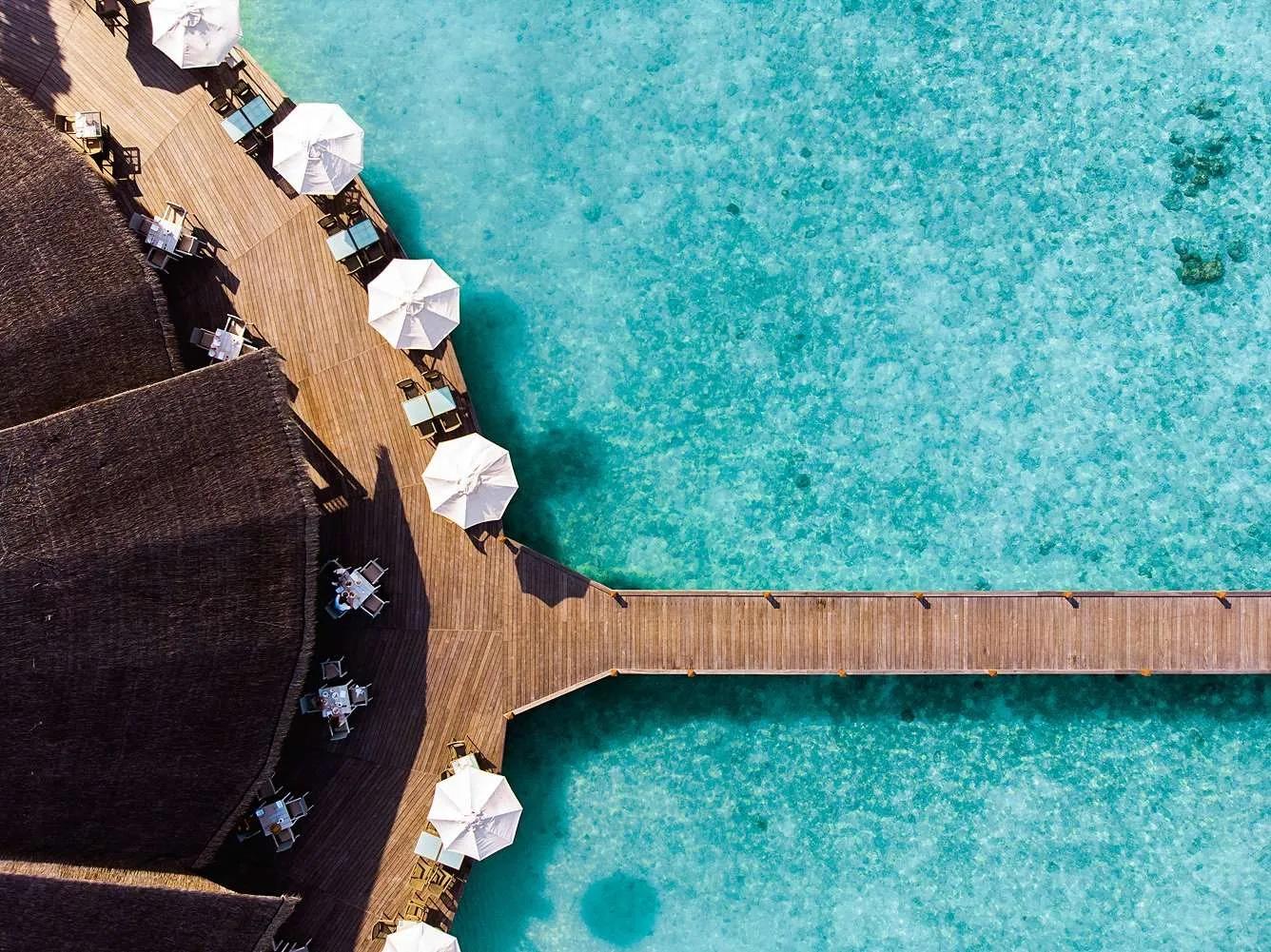Aerial view of Matheefaru Restaurant's oceanfront deck and umbrellas at Hideaway Beach Resort & Spa