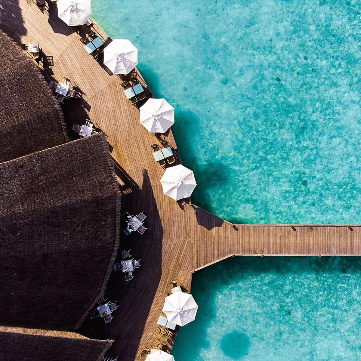 Aerial view of Matheefaru Restaurant's oceanfront deck and umbrellas at Hideaway Beach Resort & Spa