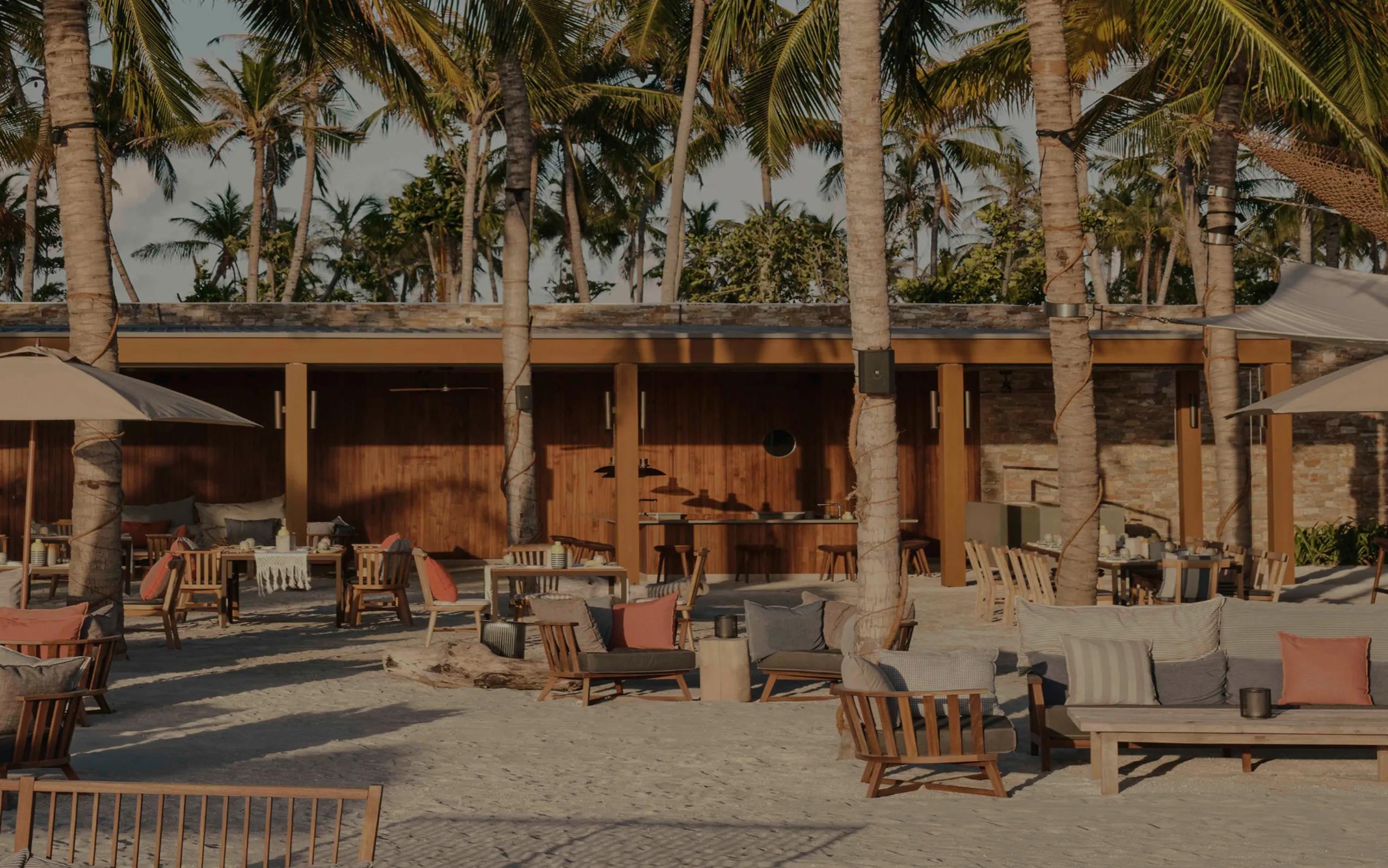 Helios' open-air dining terrace under a canopy of palms, tables and lounge seating set for golden-hour service