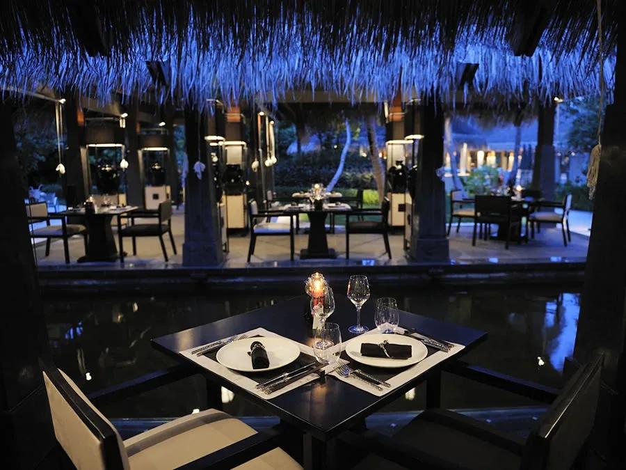 An intimate table at Kai, lit blue beneath the thatch roof at dusk