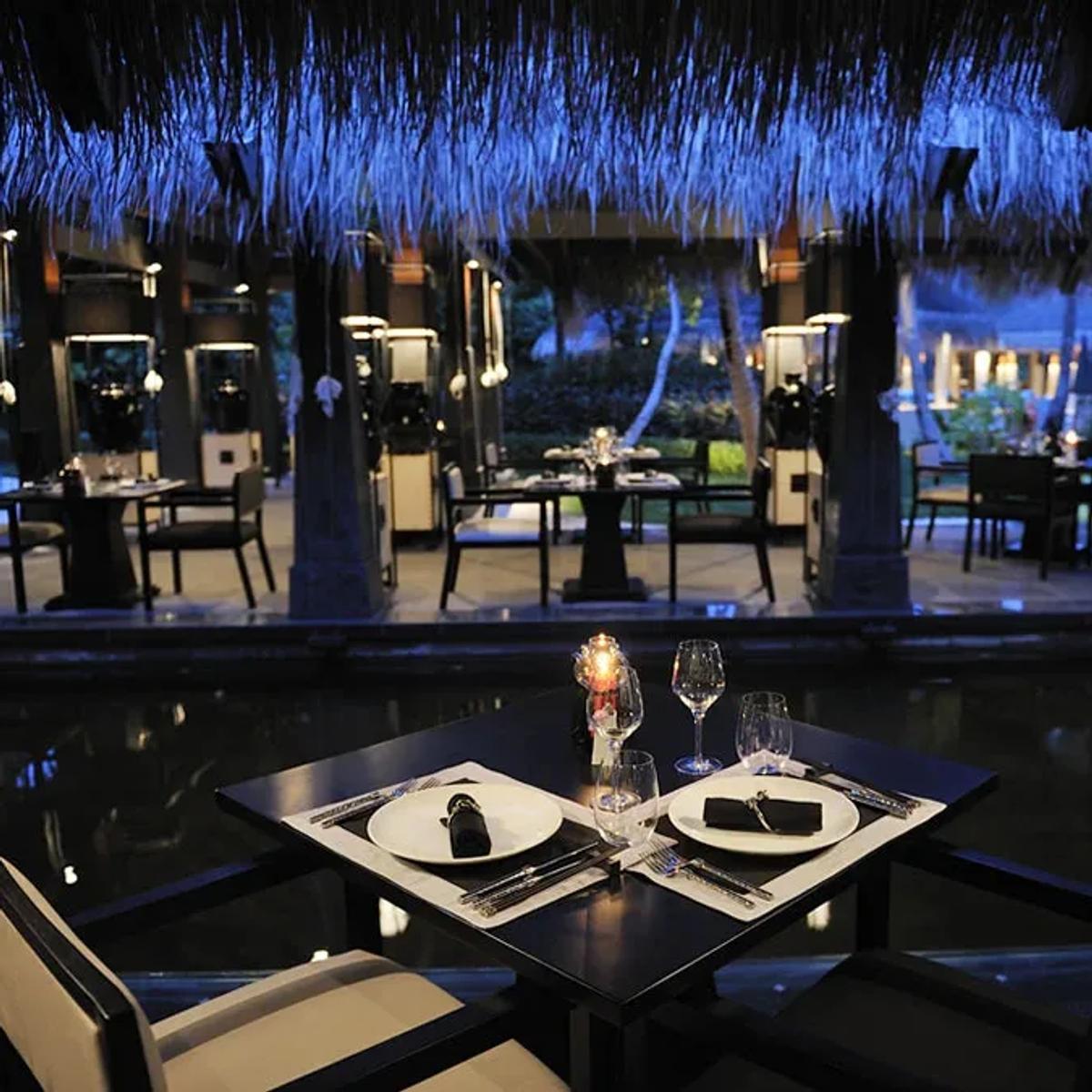 An intimate table at Kai, lit blue beneath the thatch roof at dusk