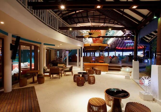 Coral Bar & Lounge at night, low seating and a lit bar beside the main pool