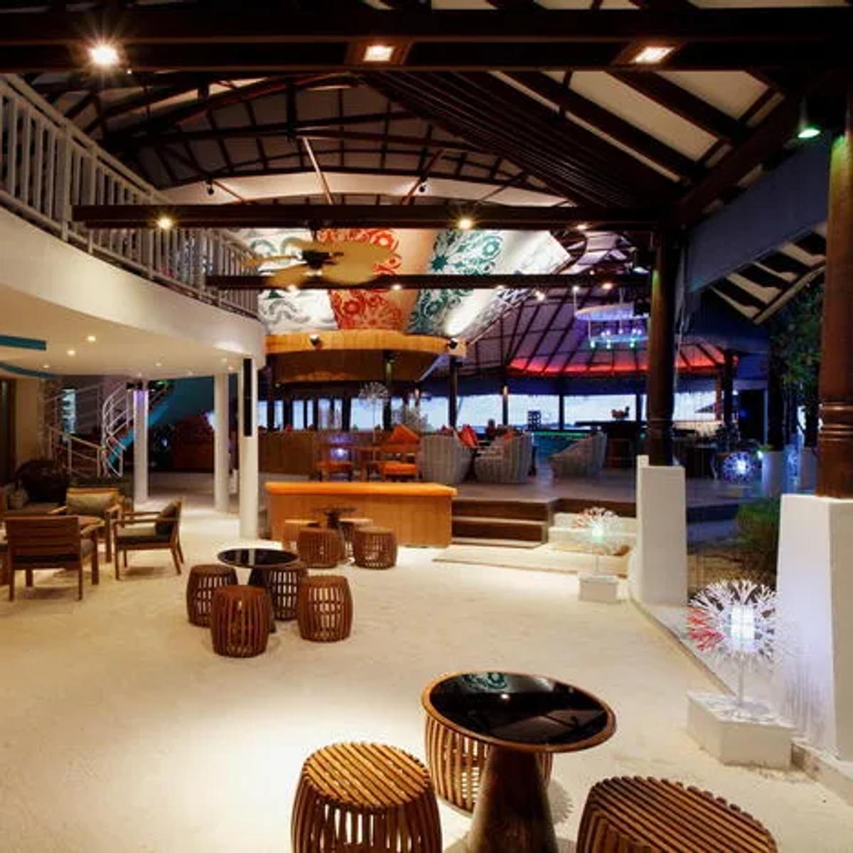 Coral Bar & Lounge at night, low seating and a lit bar beside the main pool